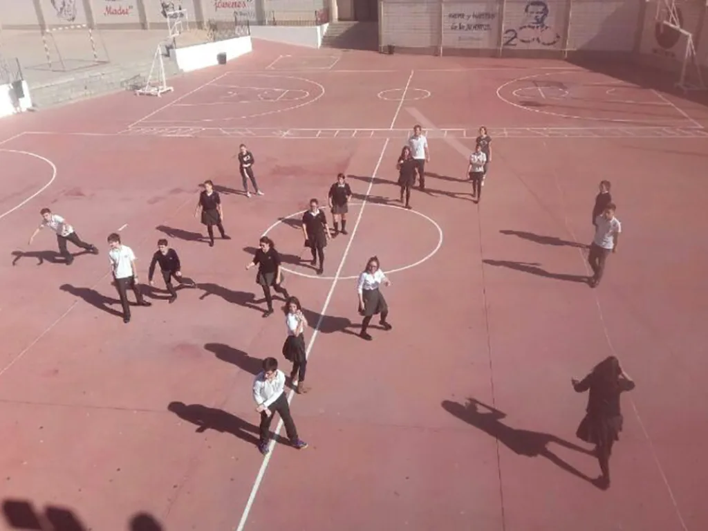 Blick von oben auf einen roten Sportplatz, auf dem Kinder spielen.